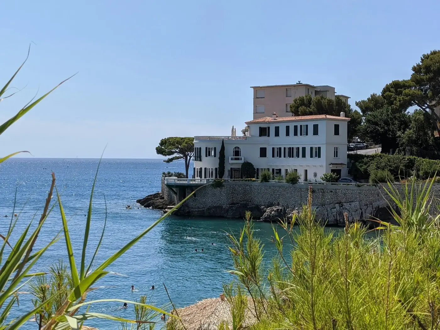 Villa blanche posée sur les rochers, au-dessus d'une crique turquoise